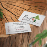Carte de visite recto verso de l'entreprise Barf & attrapes posée sur un rondin de bois