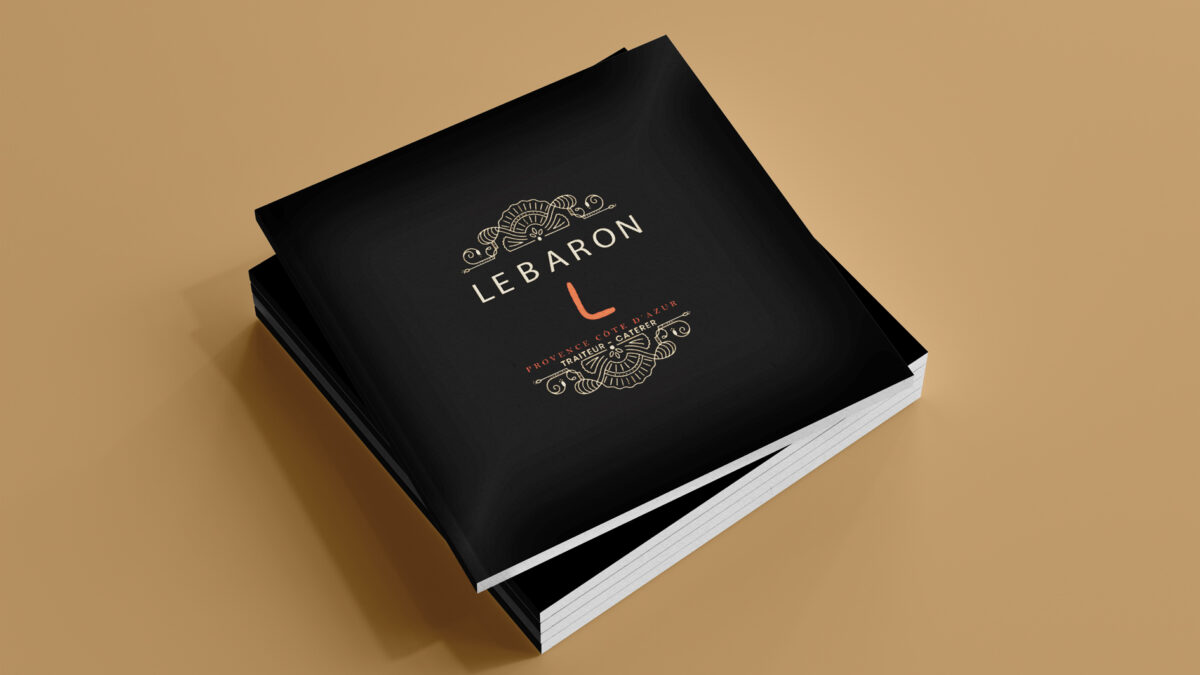 Plusieurs brochures empilées representant la couverture de la brochure haut de gamme pour Le Baron Traiteur du menu sur fond ocre