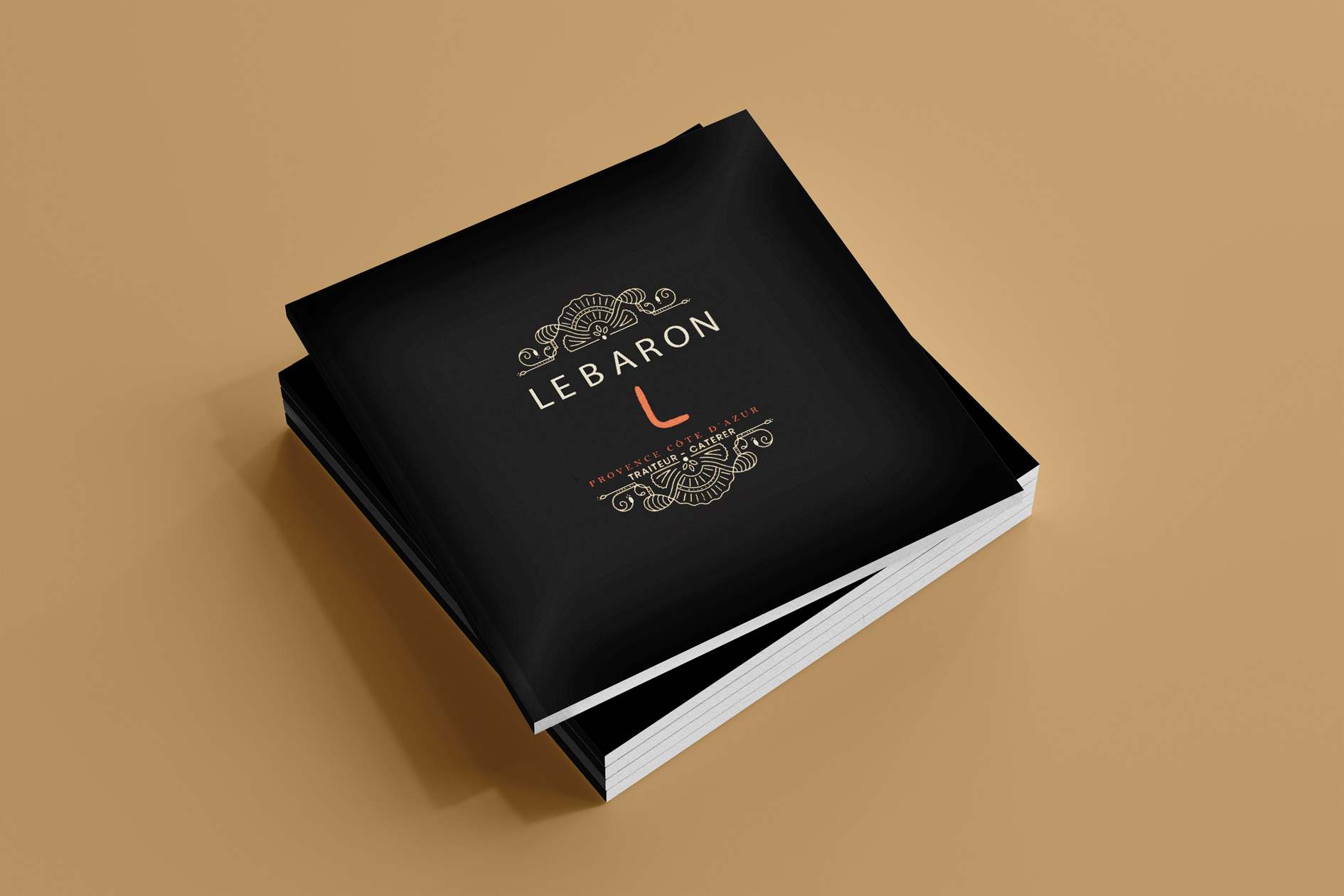 Plusieurs brochures empilées representant la couverture de la brochure haut de gamme pour Le Baron Traiteur du menu sur fond ocre